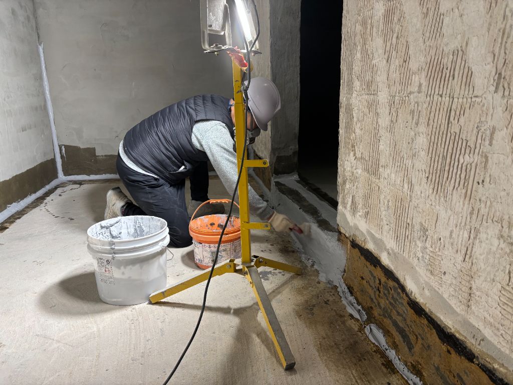 프라이머 도포 — 작업자가 벽면 하단에 프라이머를 바르고 있다