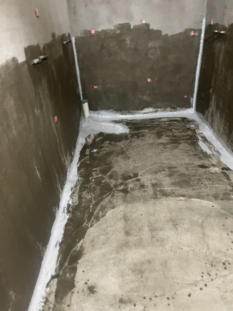 샤워실 바닥 미장 상태 — 배수 배관 돌출 및 벽 하단 실란트 보강