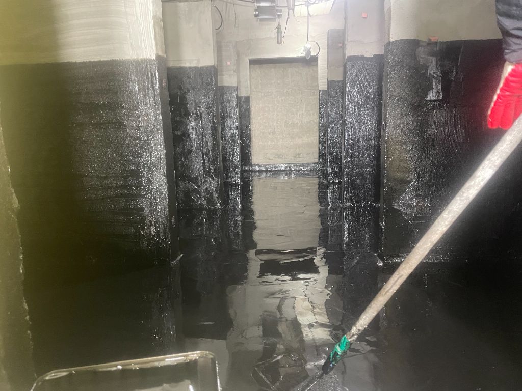 우레탄 중도 완료 전경 — 복도형 샤워실 전체가 검은색으로 코팅. 칸막이벽 여러 개가 보인다