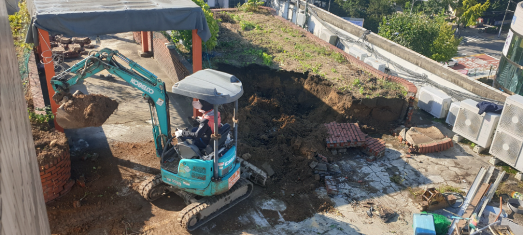 미니 굴삭기가 옥상 화단 흙을 퍼내는 작업 장면