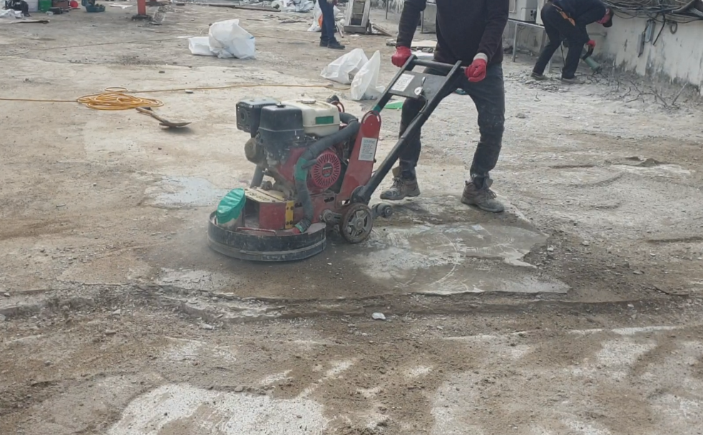 넓은 바닥면에서 연삭기로 바탕면을 정리하는 작업 장면