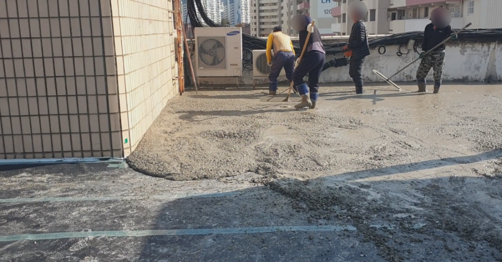 작업자들이 콘크리트를 고르게 펴는 작업 장면