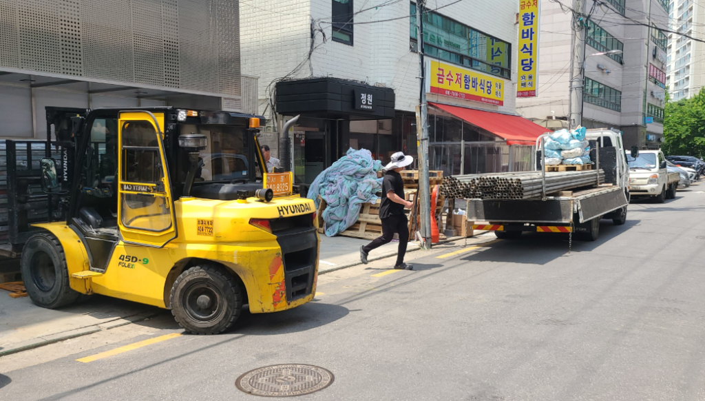 현대 45D-9 지게차로 자재를 하역하고 카고 트럭에서 강관을 내리는 모습