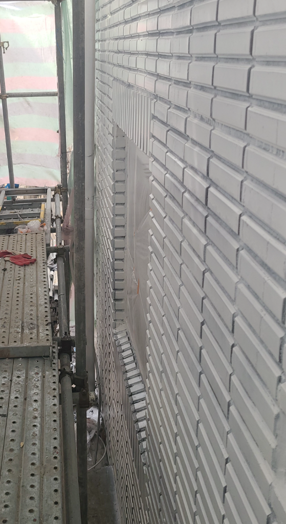 매직탄 2차 도포까지 완료된 외벽 — 적갈색 벽돌이 깔끔한 회색으로 마감