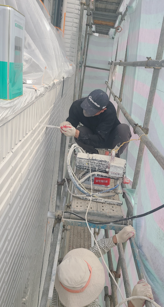 작업자 2명이 아시바 위에서 매직탄을 도포하는 모습 — 삼화페인트 에어리스 장비 사용