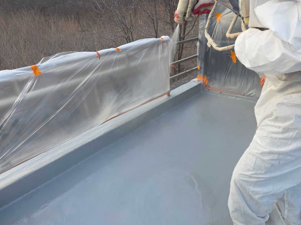 폴리우레아 고압 스프레이 도포 — 역광 속 2인 작업